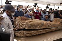Archeolog otevírá za přítomnosti novinářů a úředníků jeden ze sarkofágů z archeologického naleziště v Sakkáře.