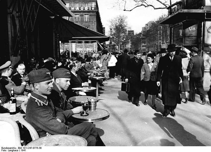 Němečtí příslušníci Luftwaffe v pařížské kavárně v roce 1941. Němci si užívali Paříž jako dovolenou, její rodilé občany však jejich přítomnost rozhořčovala a ponižovala