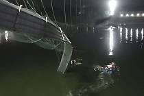 Nejméně 81 lidí zemřelo 30. října 2022 při zřícení visutého mostu pro pěší v indickém státě Gudžarát. Na snímku záchranáři prohledávají řeku v okolí zříceného mostu.