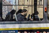 Lidé s rouškami na obličejích jako ochranou proti koronaviru 18. března 2020 cestují poloprázdnou tramvají na Náměstí Míru v Praze