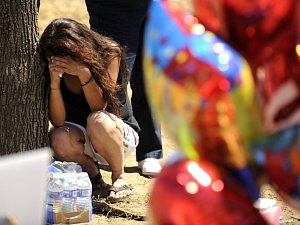 Žena truchlí u pomníku za oběti střelby v americkém Denveru.