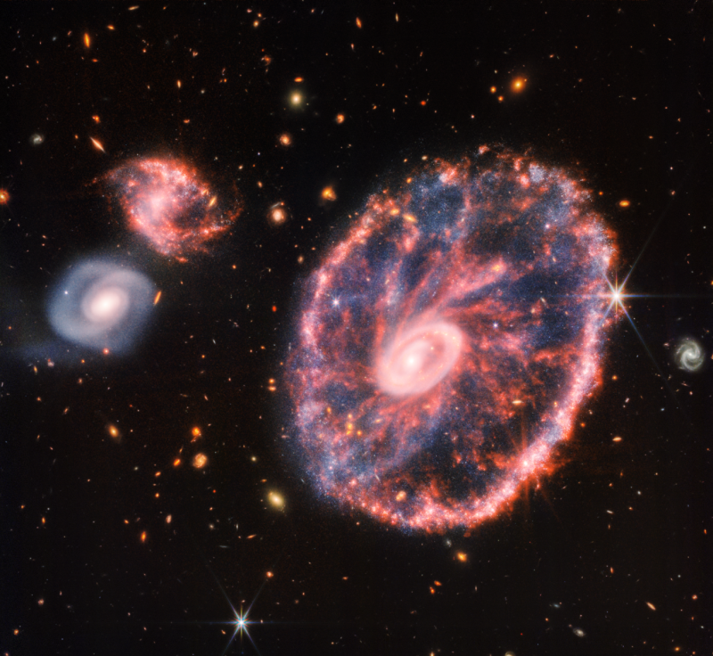 Snímek zachycený pomocí kamery NIRCam i nástrojem MIRI zachycující velkou galaxii připomínající kolo od vozu. Doprovází ji dvě menší spirální galaxie přibližně stejné velikosti.