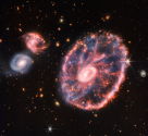 Snímek zachycený pomocí kamery NIRCam i nástrojem MIRI ukazuje velkou galaxii připomínající kolo od vozu. Doprovází ji dvě menší spirální galaxie přibližně stejné velikosti.