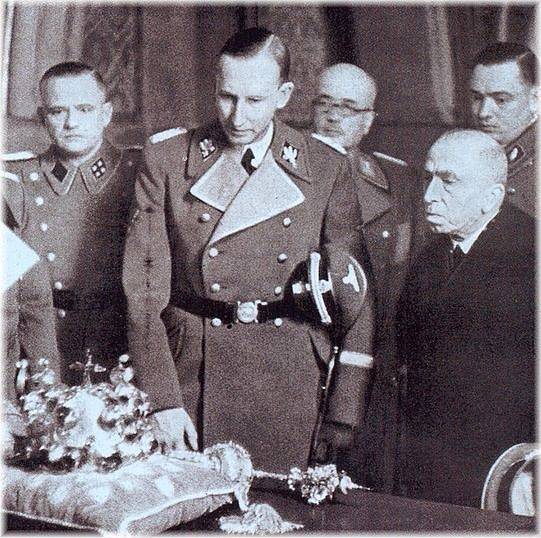 Zastupující říšský protektor Reinhard Heydrich si v doprovodu protektorátního prezidenta Emila Háchy prohlíží české korunovační klenoty
