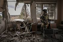 Ukrajinský voják na snímku z 27. března prochází budovou ve vesnici Stojanka u Kyjeva, silně poničenou ruskými útoky