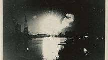 Noční bombardování okolí neidentifikované řeky v Evropě během druhé světové války (pravděpodobně jde o oblast Antverp v Belgii). S klesajícími hladinami vod se dávno svržené bomby znovu vynořují z říčního dna