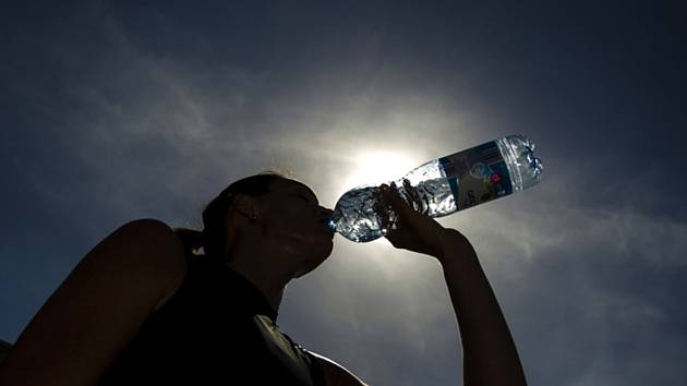 Dívka se osvěžuje balenou vodou během horkého dne - Ilustrační foto