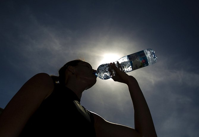 Dívka se osvěžuje balenou vodou během horkého dne - Ilustrační foto