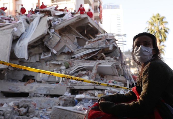 Obyvatelka Izmiru sleduje 31. října 2020 turecké záchranáře při prohledávání trosek jedné z budov po zemětřesení, které město postihlo o den dříve