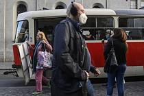 Lidé s rouškami na obličejích na tramvajové zastávce v Praze na Andělu
