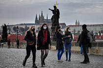 Lidé v rouškách 22. října 2020 na pražském Karlově mostě. Kvůli šíření nemoci covid-19 vstoupilo v platnost vládní nařízení omezení pohybu a kontaktu s jinými lidmi. Výjimkou jsou cesty do práce, na nákupy, k lékaři nebo za rodinou