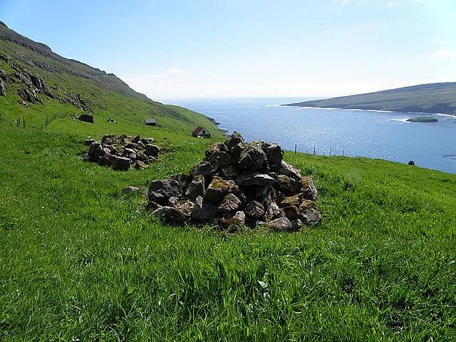 Pohled na fjord Hov na Faerských ostrovech. Kamenné mohyly představují hrob vikingského náčelníka Havgrímura a údajně i jeho koně, jenž má být pohřben pod mohylou v popředí. Havgrímur spočívá v hrobě za ní