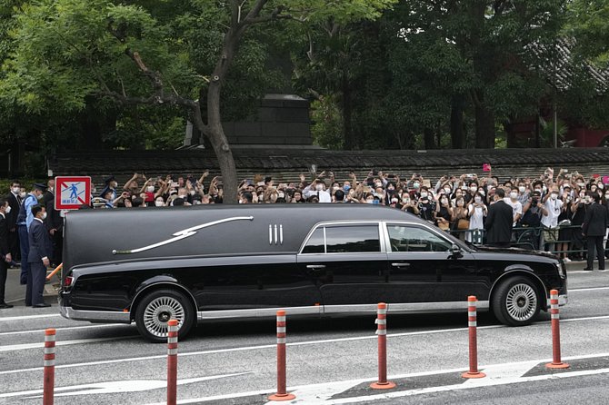 Vozidlo s ostatky bývalého japonského premiéra Šinzóa Abeho odjíždí z buddhistického chrámu Zojoji v centru Tokia 12. července 2022
