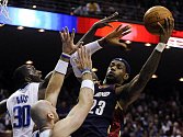 Hvězda basketbalistů Clevelandu LeBron James (v tmavém) se snaží prosadit přes bránícího dvojblok Bass, Gortat. 