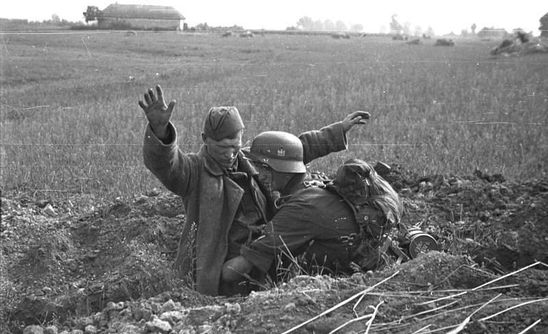 Německý voják odzbrojuje sovětského vojáka ve střeleckém zákopu