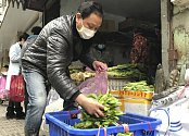 Prodavač zeleniny na trhu v čínském městě Wu-chan