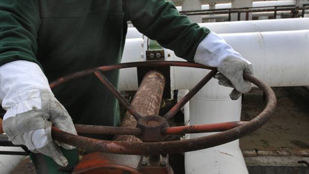 Pracovník rafinérské společnosti uzavírá potrubí s ropou. Ilustrační foto
