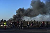 Lidé v ukrajinském Lvově sledují kouř stoupající nad místem výbuchu poblíž letiště, 18. března 2022.