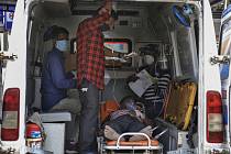 Pacient s covidem-19 čeká v sanitce za pomoci příbuzných na přijetí v nemocnici v indickém městě Ahmadábád