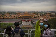 Lidé v rouškách v pekingu 25. dubna 2020, v pozadí turistická atrakce Zakázané město