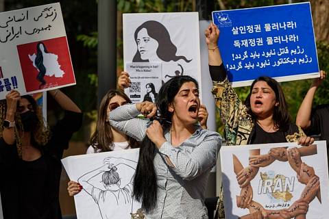 Íránská demonstrantka si stříhá vlasy na demonstraci kvůli smrti Mahsy Amíníové v jihokorejském Soulu.