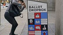 Muž hází hlasovací lístek do volební schránky před veřejnou knihovnou v americkém Bostonu