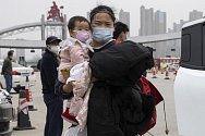 Žena v roušce držící dítě v čínském Wu-chanu (na snímku z 3. března 2020)