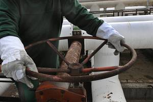 Pracovník rafinérské společnosti uzavírá potrubí s ropou. Ilustrační snímek