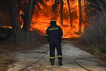 Hasič se snaží uhasit lesní požár u plážového letoviska Vatera na řeckém ostrově Lesbos ve východním Egejském moři