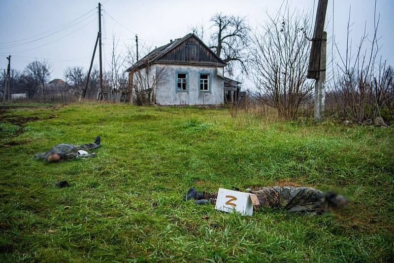 Upozorňujeme, že následující fotografie jsou drastické: Na snímku těla dvou ruských vojáků leží na trávě před domem v nedávno osvobozené vesnici Makijivka na Donbasu.