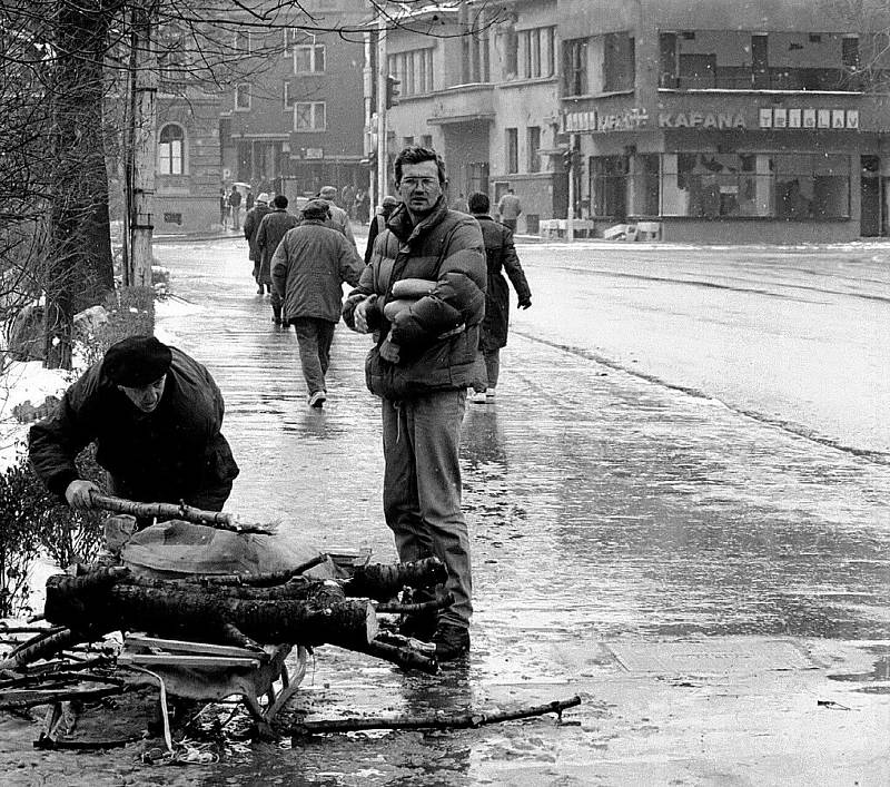 Život v obležení, Sarajevo, zima 1992-1993. Sběr větví na palivové dříví. Muž vpravo drží v náručí vzácné bochníky chleba