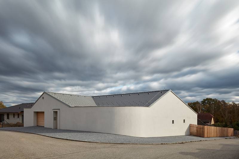 Na velkém pozemku v Litvínovicích architekti postavili minimalistický bílý objekt s netradičně zaobleným rohem místo plotu.