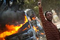 Libyjský muž vedle hořícího autobusu na silnici vedoucí do předměstí Benghází.