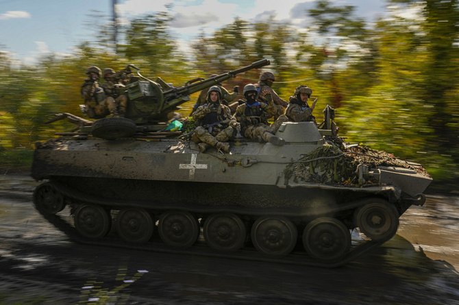 Ukrajinští vojáci na obrněném vozidle projíždějí vesnicí Šandrygolovo, která leží nedaleko města Lyman, 4. října 2022
