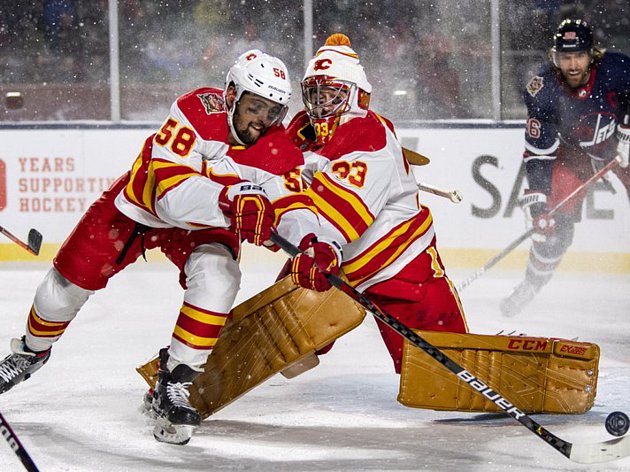 Hokejisté Calgary Flames Oliver Kylington (vlevo) a brankář David Rittich (33) v utkání s Winnipegem Jets v utkání NHL pod otevřeným nebem.