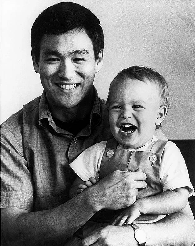 Slavný herec Bruce Lee drží v náručí malého syna Brandona. Netušil, že ani jednomu z nich nebude dopřán dlouhý život. Bruce Lee zemřel na následky otoku mozku, Brandona usmrtil projektil vypálený nešťastně přímo na place