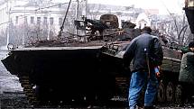 Čečenský ozbrojenec běží kolem spáleného ruského obrněného vozidla (BMP-2) během bitvy o Groznyj
