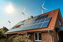 Solární panely na střeše domu a větrné turbíny - koncept udržitelných zdrojů.