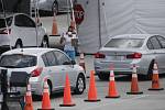 Zdravotnice v roušce se pohybuje mezi auty, která stojí ve frontě v americkém Miami Gardens. Řidiči čekají na testování na covid-19.