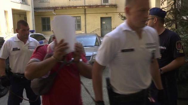 Maďarská policie odvádí jednoho ze čtyř mužů podezřelých z podílu na smrti 71 uprchlíků v chladírenském voze na východě Rakouska (snímek z 29. srpna 2015)