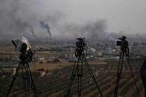 Televizní kamery v turecké obci Çeylanpinar na hranici se Sýrií na snímku z 16. října 2019. Na obzoru je vidět kouř stoupající nad syrským městem Rás al-Ajn po útocích turecké  armády.