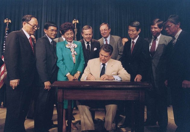Ronald Reagan podepisuje v srpnu 1988 zákon, který po více než 40 letech přiznal japonským Američanům odškodnění za jejich věznění v internačních táborech.