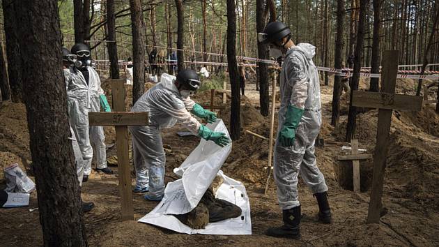 Pracovníci exhumují tělo na provizorním pohřebišti ve východoukrajinském Izjumu, 17. září 2022.