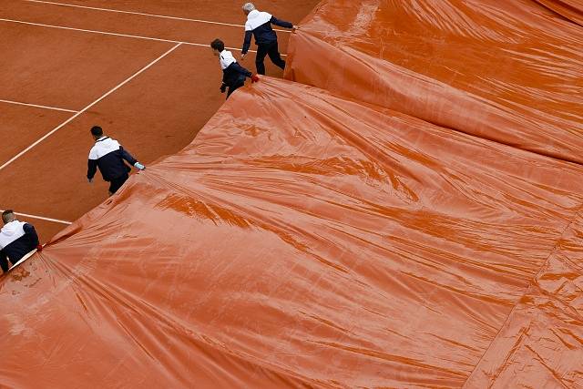 Pořadatelé French Open při dešti zakrývají kurt plachtou.