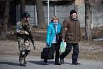 Ukrajinský voják doprovází dvojici civilistů v okrajové části města Irpiň