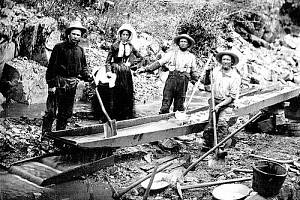Čtveřice zlatokopů, tři muži a jedna žena, rýžují zlato během kalifornské zlaté horečky