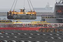 Jeřáb nakládá na loď potrubí pro plynovod Nord Stream 2 v baltském přístavu Mukran