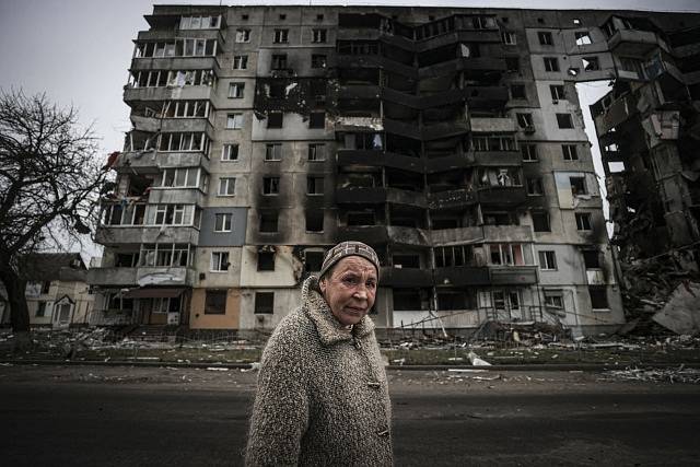Žena před zničenou budovou v ukrajinské Boroďance.