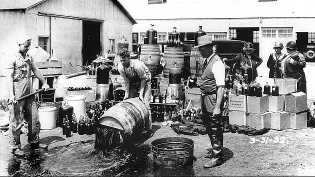 V roce 1932 trvala ve Spojených státech ještě stále prohibice, která přispěla k nárůstu organizovaného zločinu a ke vzniku éry veřejného nepřítele. Na snímku americká policie v Santa Aně vylévá nelegální alkohol