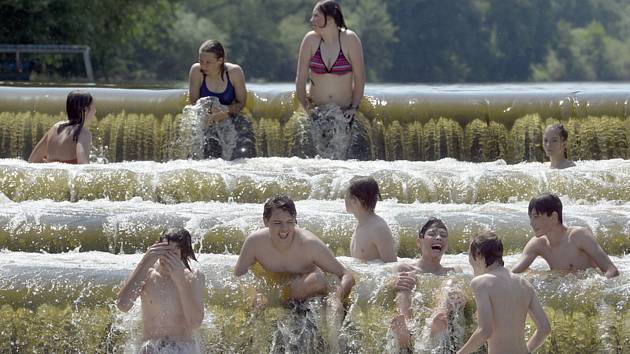 Lidé se v horkém letním počasí koupají u jezu. Ilustrační snímek